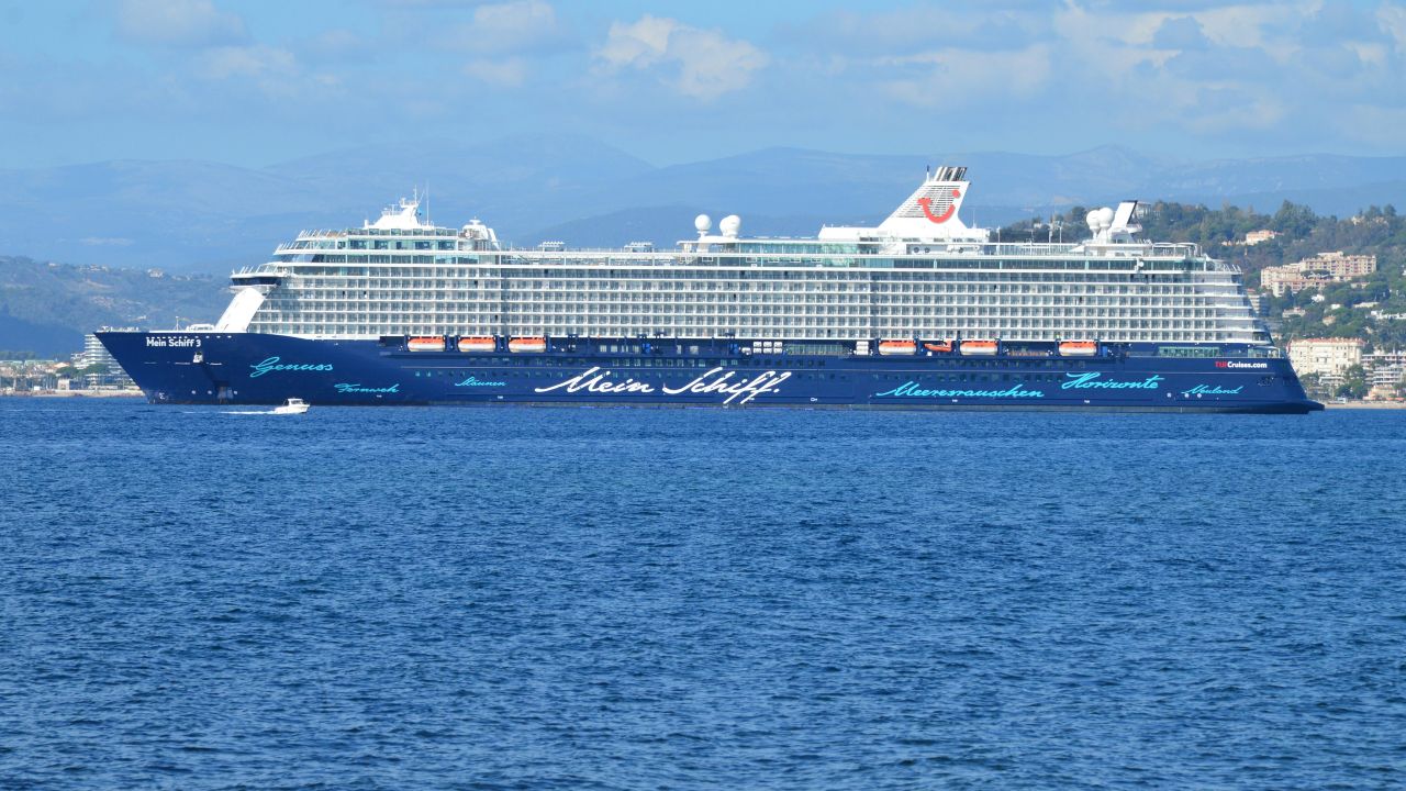 heros-img A luxury cruise ship named Mein Schiff sails across the ocean under a clear blue sky.
