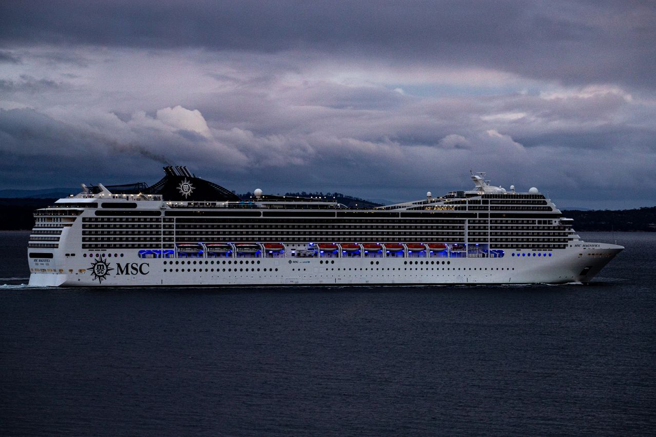 about-us MSC cruise ship navigating waters near Hobart, Tasmania against a dramatic cloudy sky.